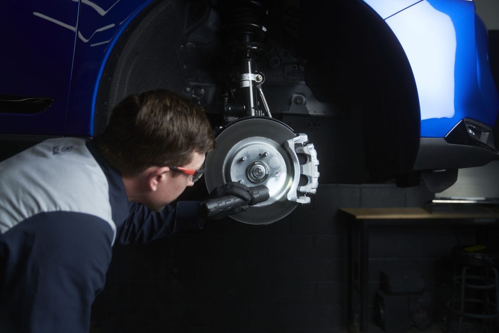 Technician inspecting a car’s brake in a workshop.